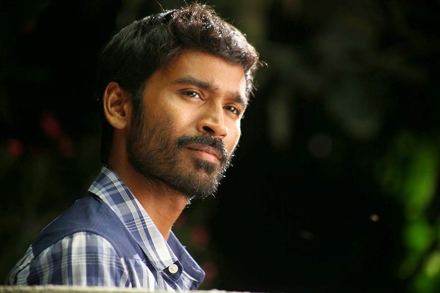 Dhanush in a contemplative outdoor portrait wearing a blue plaid shirt HD wallpaper