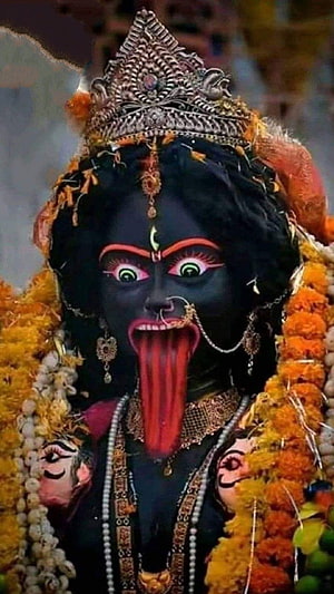 Close-up of Kali Maa Idol with Black Skin, Protruding Tongue, and Marigold Garlands HD phone wallpaper