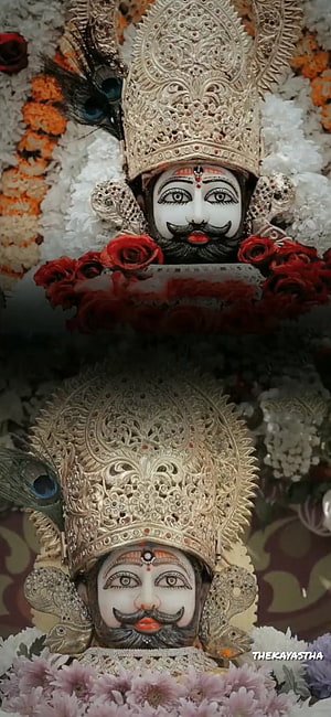 Ornate Silver Crowned Hindu Deity Statue Adorned With Peacock Feathers And Red Roses HD phone wallpaper