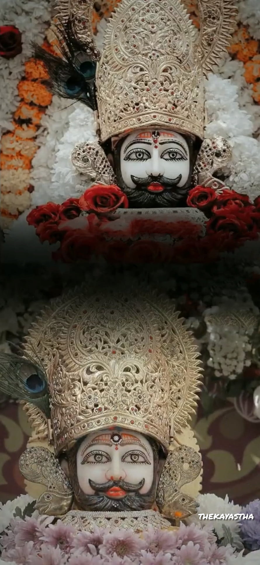 Ornate Silver Crowned Hindu Deity Statue Adorned With Peacock Feathers And Red Roses HD phone wallpaper