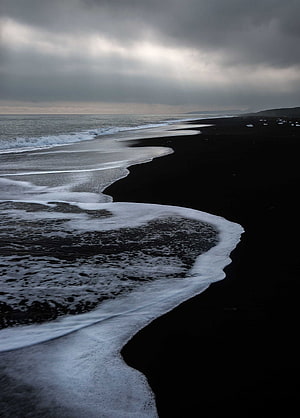 Dramatic Black Sand Beach with White Sea Foam Under Overcast Sky HD phone wallpaper
