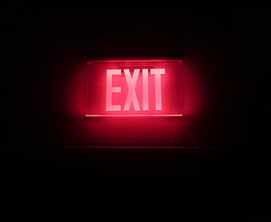 Glowing Red Neon Exit Sign Against a Pitch Black Background HD wallpaper