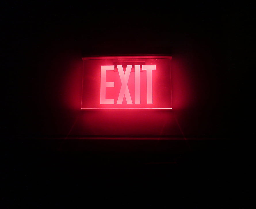 Glowing Red Neon Exit Sign Against a Pitch Black Background HD wallpaper