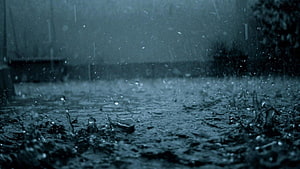 Moody Close-Up of Rain Droplets Splashing on Wet Ground in a Dark Urban Setting HD wallpaper