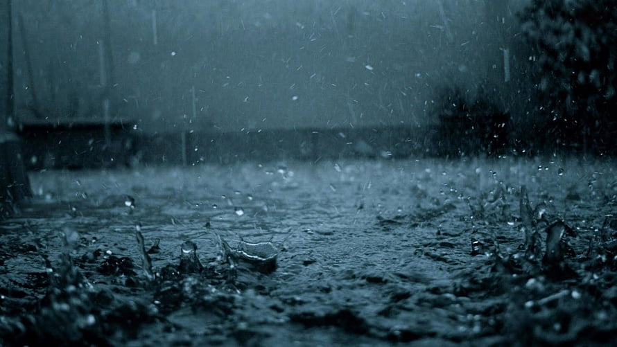 Moody Close-Up of Rain Droplets Splashing on Wet Ground in a Dark Urban Setting HD wallpaper