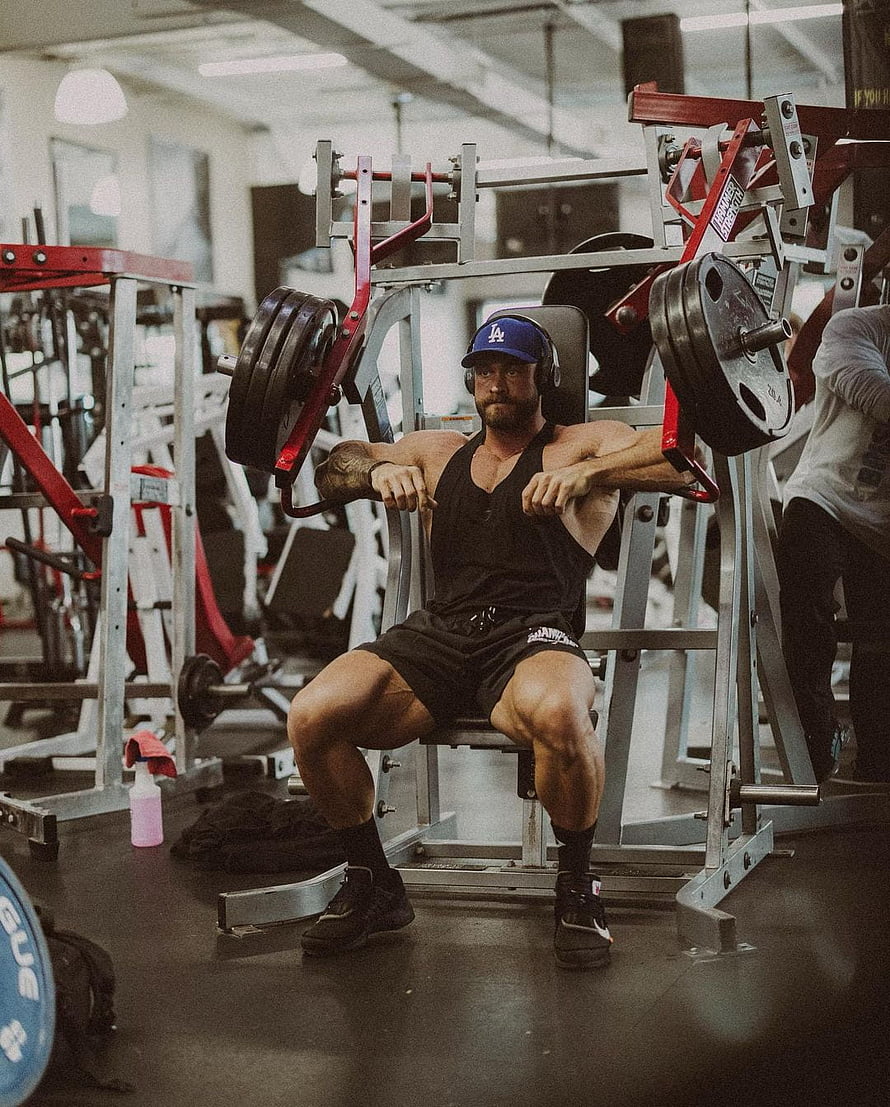 Muscular Man Wearing Blue LA Cap Performing Seated Chest Press Workout in Gym, cbum, chris, exercise_equipment, thigh, chris_bumstead, gym, bum HD phone wallpaper