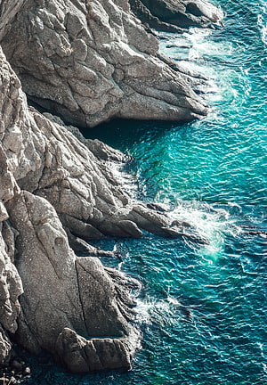 Turquoise Ocean Waves Crashing Against Rugged Coastal Rock Formations HD phone wallpaper