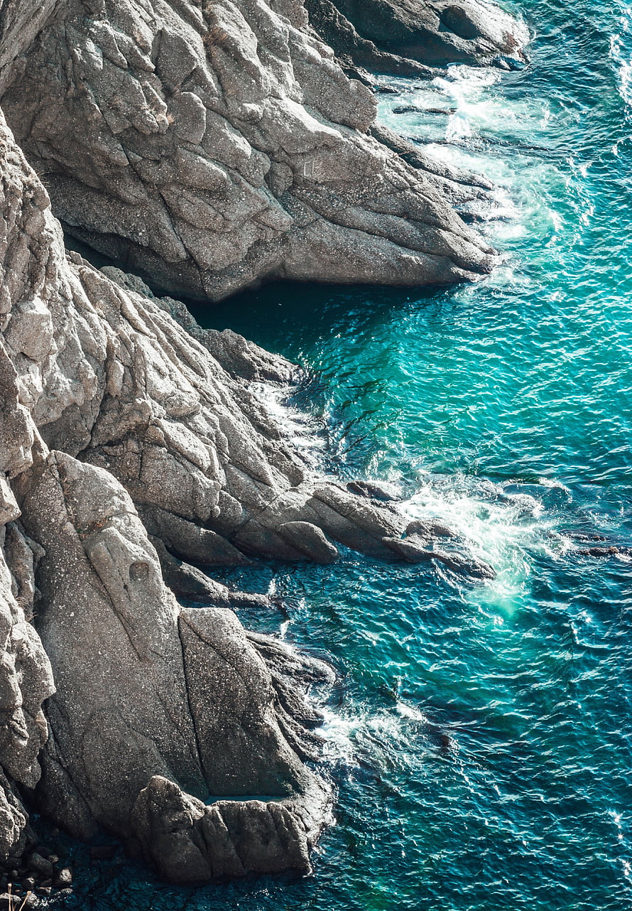 Turquoise Ocean Waves Crashing Against Rugged Coastal Rock Formations HD phone wallpaper