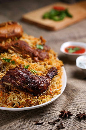 Chicken Biryani with Roasted Drumsticks and Spiced Rice on a Rustic Table HD phone wallpaper
