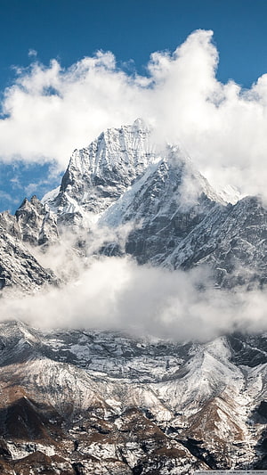 Majestic Snow-Capped Himalayan Peak Emerging Through Dramatic Clouds Under a Clear Blue Sky HD phone wallpaper