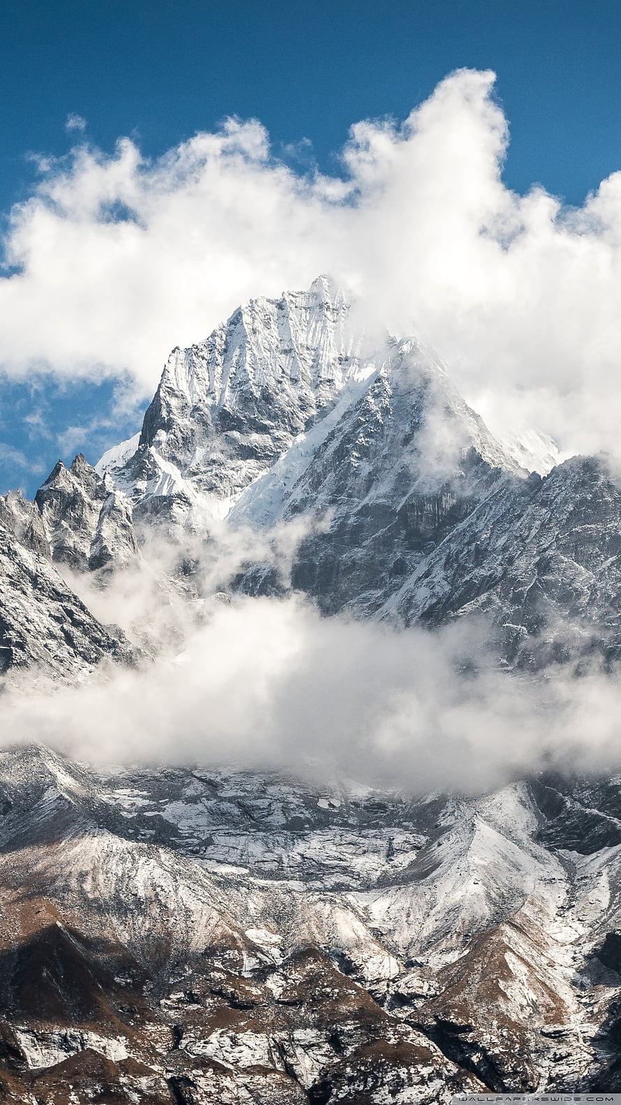 Majestic Snow-Capped Himalayan Peak Emerging Through Dramatic Clouds Under a Clear Blue Sky HD phone wallpaper