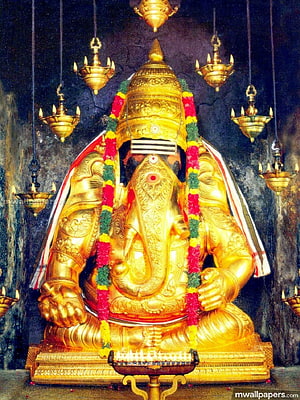 Golden Karpaga Vinayagar Ganesha Statue with Flower Garland and Hanging Oil Lamps HD phone wallpaper