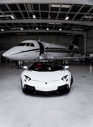 White Lamborghini Aventador parked in front of a private jet inside a hangar HD phone wallpaper