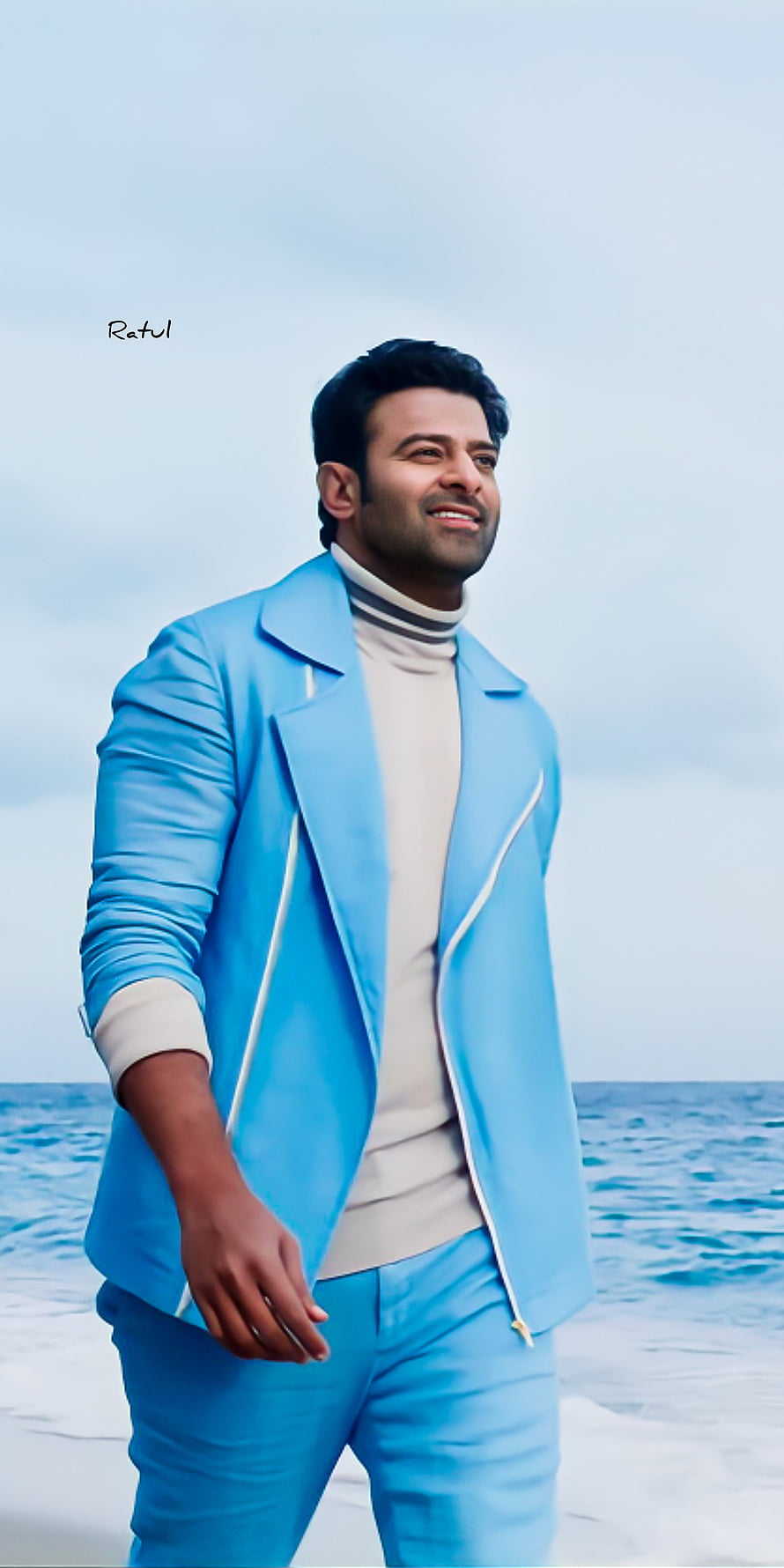 Prabhas in a light blue suit standing on a beach with the ocean and sky in the background HD phone wallpaper