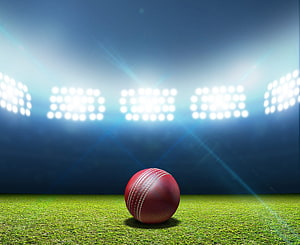 Red Cricket Ball on Green Pitch Under Bright Stadium Floodlights at Night HD wallpaper