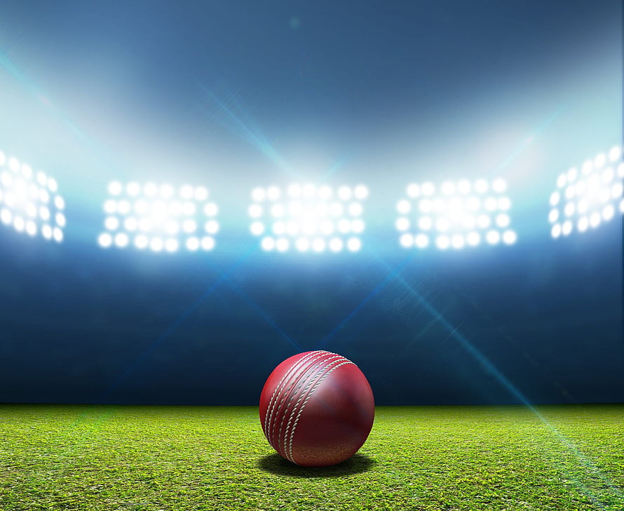 Red Cricket Ball on Green Pitch Under Bright Stadium Floodlights at Night HD wallpaper