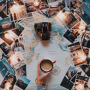 Travel planning setup with vintage camera, world map, coffee cup, and scattered photos HD phone wallpaper