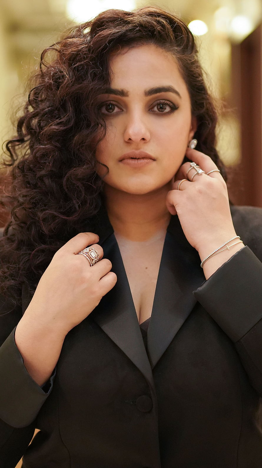 Nithya Menon in a black blazer with curly hair and elegant jewelry HD phone wallpaper