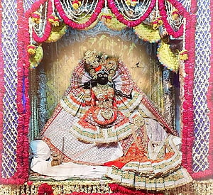 Lord Jagannath deity adorned in ornate silk garments and jewelry within a decorated temple shrine HD wallpaper
