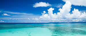 Stunning Turquoise Ocean View With Fluffy White Clouds And Distant Mountains HD wallpaper