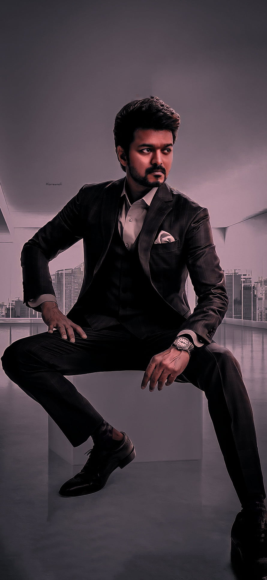 Thalapathy Vijay in a dark three-piece suit seated against a modern city skyline backdrop HD phone wallpaper