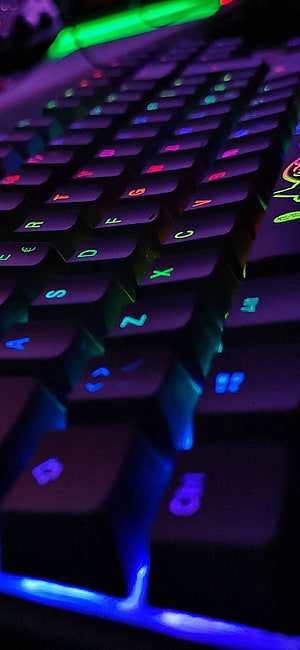Close-up of a mechanical gaming keyboard with vibrant RGB backlighting and colorful illuminated keys HD phone wallpaper