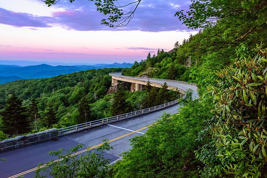 Winding Mountain Highway at Sunset with Lush Forest and Distant Blue Ridges HD wallpaper
