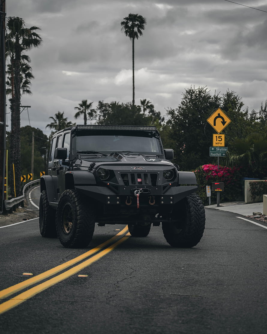 Black Modified Jeep Wrangler with Off-Road Bumper and LED Light Bar on Coastal Road HD phone wallpaper
