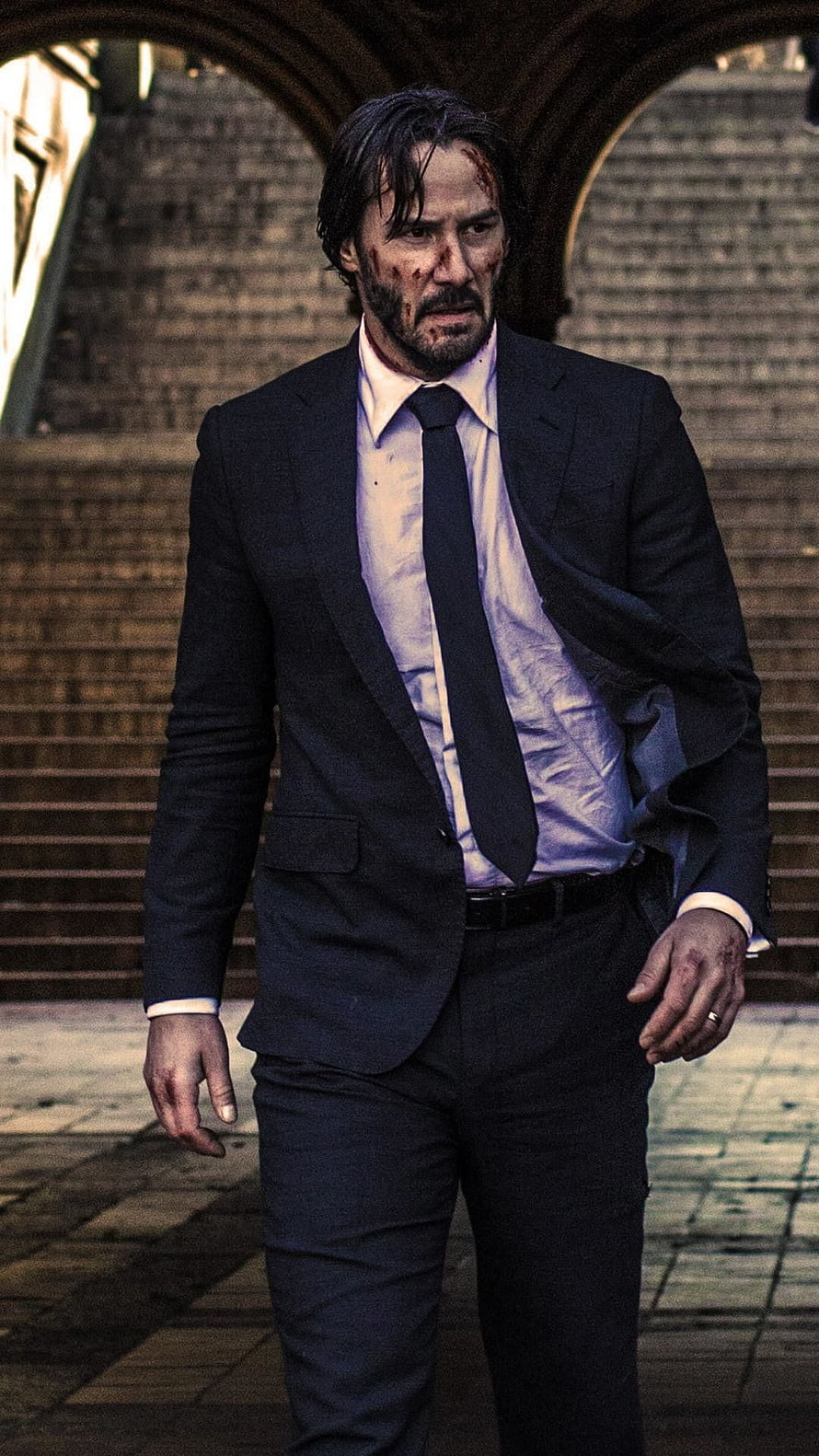 Keanu Reeves as John Wick in a dark suit with blood on his face walking through an archway HD phone wallpaper