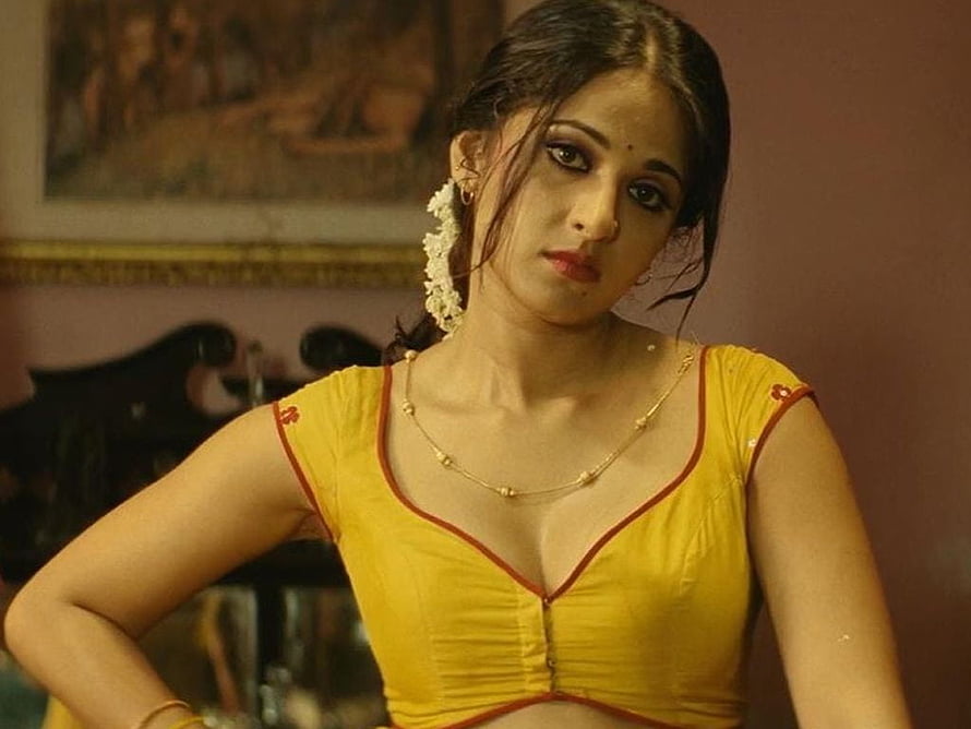 Anushka Shetty in a yellow blouse with red trim and floral hair accessory HD wallpaper