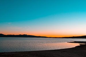 Serene Sunset Over Calm Lake With Distant Mountain Silhouette HD wallpaper