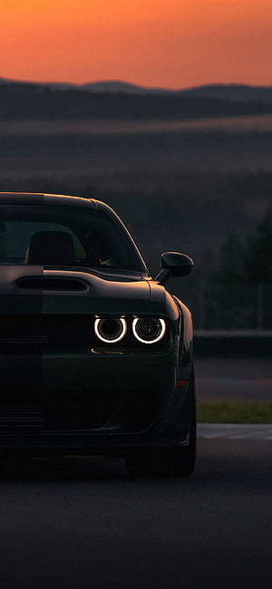 Dodge Challenger Hellcat with LED headlights at sunset on a dark road HD phone wallpaper