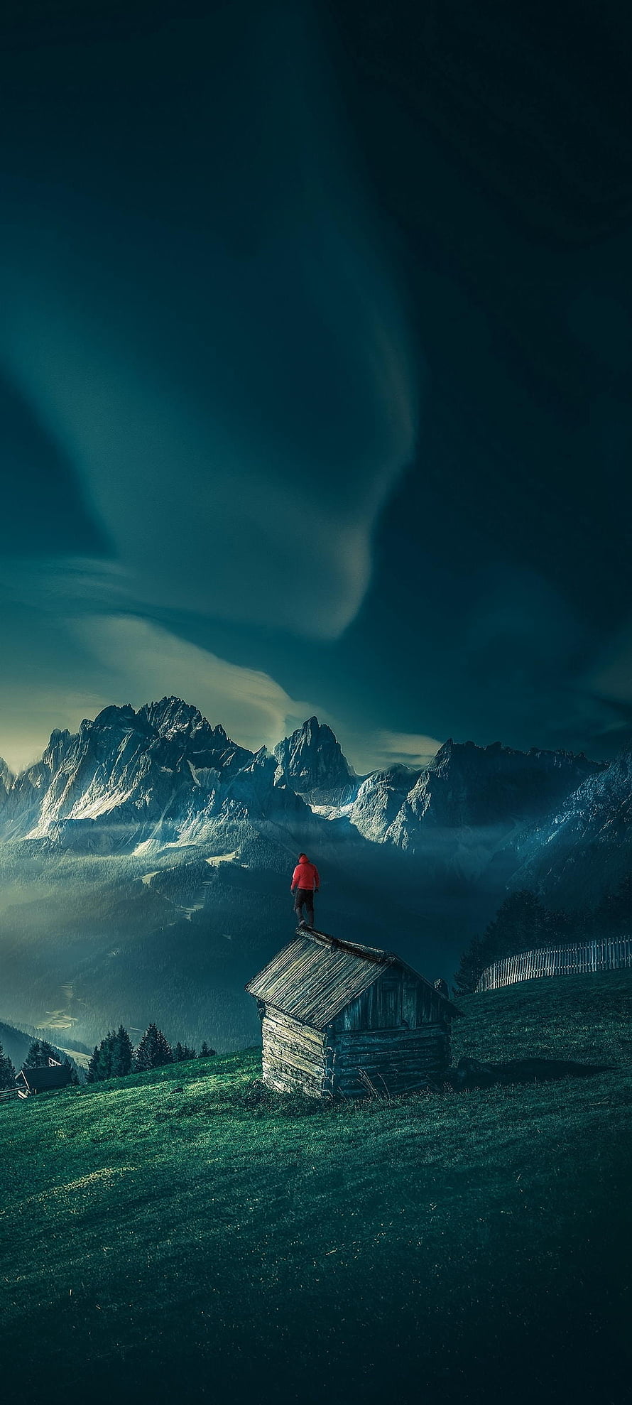 Lone Figure in Red Jacket Standing on Cabin Roof Overlooking Majestic Mountain Range HD phone wallpaper