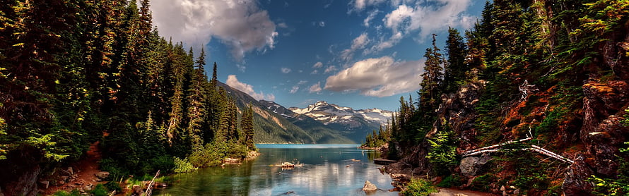 Serene Mountain Lake Surrounded by Dense Pine Forest and Snowy Peaks HD wallpaper