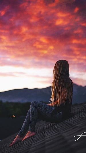 Girl Sitting on Roof Watching Vibrant Sunset Over Mountains HD phone wallpaper