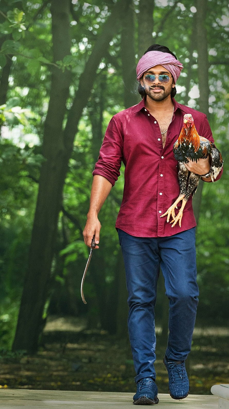 Actor Dhanush in a red shirt and turban holding a rooster and sickle in a forest setting HD phone wallpaper