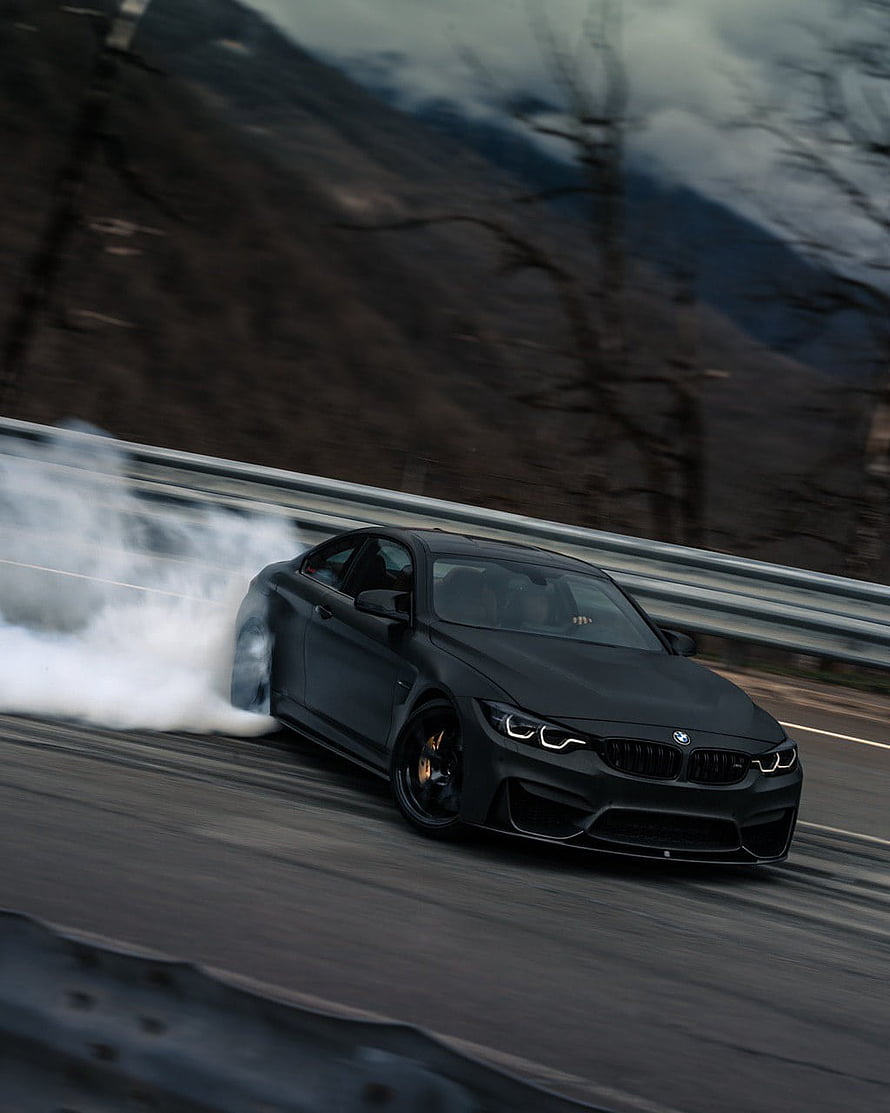 Matte Black BMW M4 Drifting on Mountain Road with Tire Smoke HD phone wallpaper