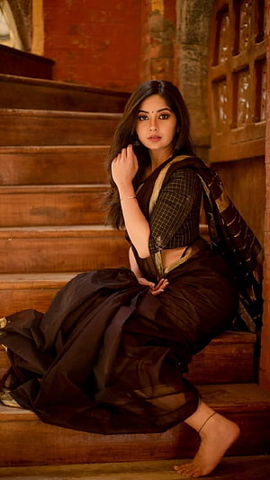 Kashmira Pardeshi in a dark brown saree seated on rustic wooden stairs HD phone wallpaper
