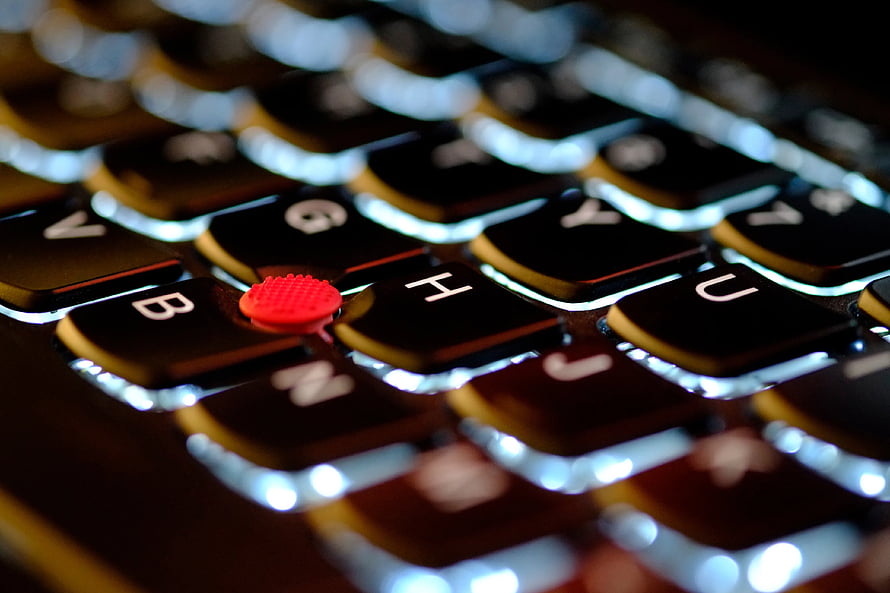 Close-up of a Lenovo ThinkPad keyboard with illuminated keys and red TrackPoint HD wallpaper