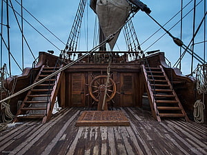 Historic Tall Ship Deck With Wooden Helm, Stairs, and Rigging Under a Blue Sky HD wallpaper