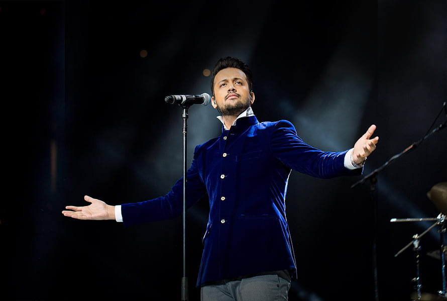Atif Aslam performing on stage in a blue velvet jacket with arms outstretched HD wallpaper