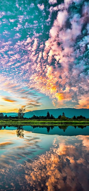 Vibrant Sunset Sky with Dramatic Clouds Reflected in a Calm Mountain Lake HD phone wallpaper