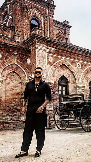 Karan Aujla in Black Kurta Standing Before Historic Brick Architecture HD phone wallpaper