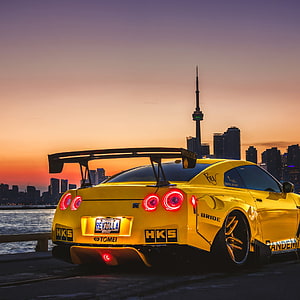 Yellow Nissan GT-R R35 with HKS and Bride Stickers Parked Near Toronto Skyline at Sunset HD phone wallpaper