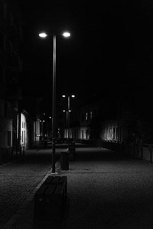 Black and white photography of an empty cobblestone street at night illuminated by streetlights HD phone wallpaper