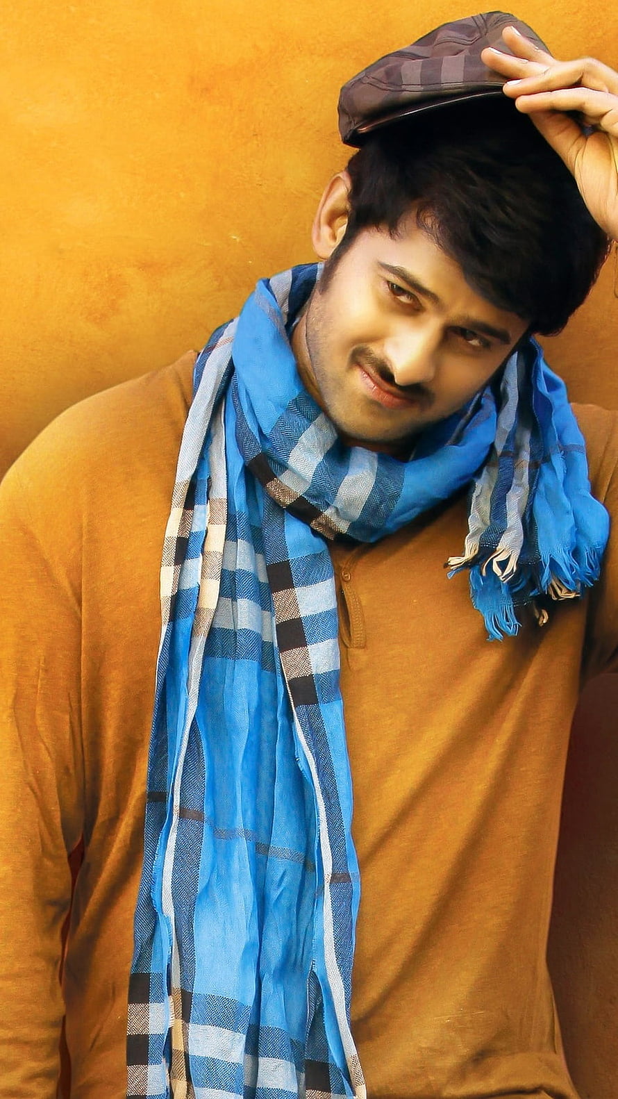 Prabhas in a mustard sweater and blue checkered scarf with a flat cap HD phone wallpaper