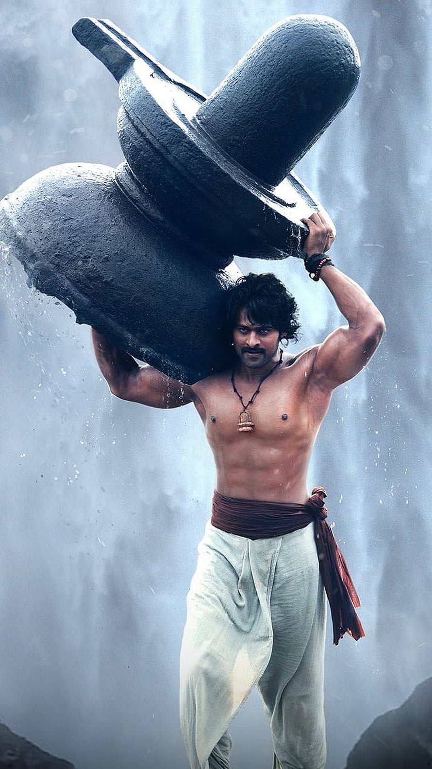 Paawan Singh as Bhairava lifting a massive stone grinder in the rain HD phone wallpaper