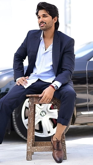 Allu Arjun in a stylish navy blue suit and white shirt sitting on a wooden stool HD phone wallpaper