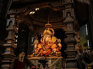 Ornate Ganesha Statue in Dark Temple Shrine with Gold Accents HD wallpaper