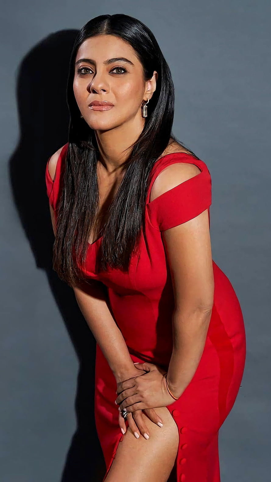 Kajol in a striking red dress with a confident pose against a grey studio backdrop HD phone wallpaper